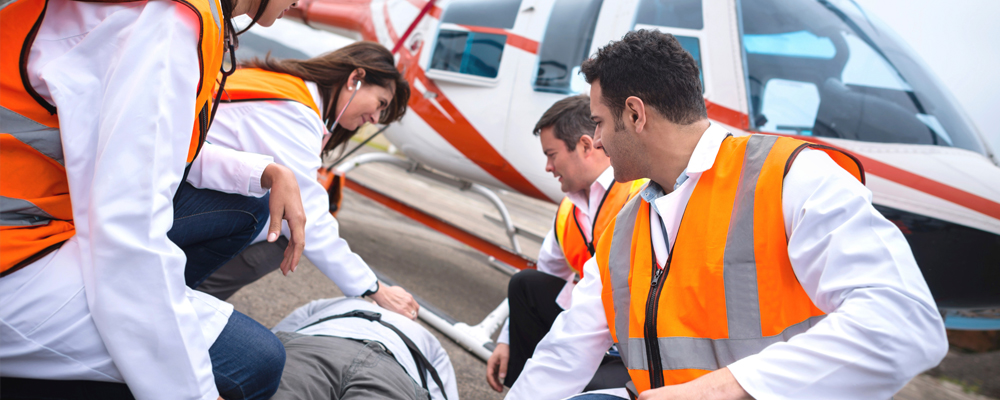 paramedics with patient in front of helicopter